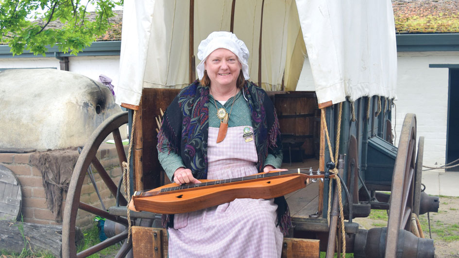 Volunteer Joan Cochrane sitting in 1850s attire at Sutter's Fort