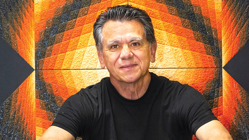 Op-Artist Henery Parada in front of red and orange geometric painting