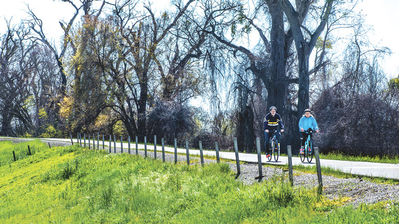 2 people riding bikes on the Sacramento River Parkway trail