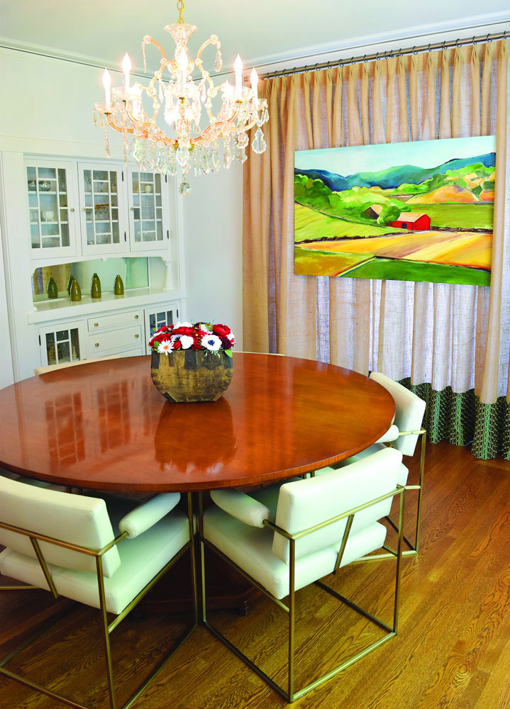 Dining room with fresh flowers on table and landscape painting on wall