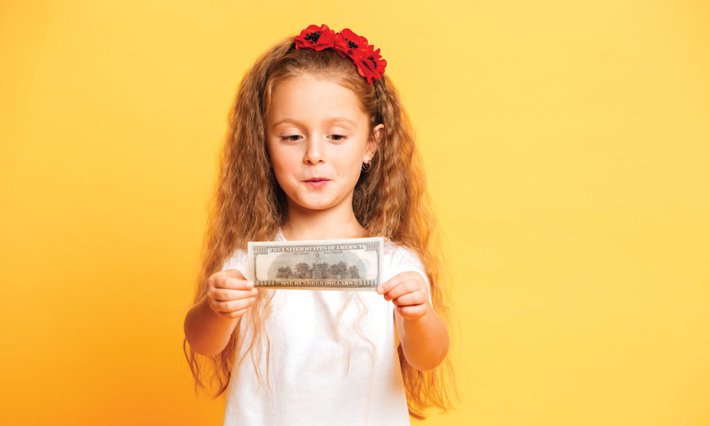 little girl looking at 100 dollar bill